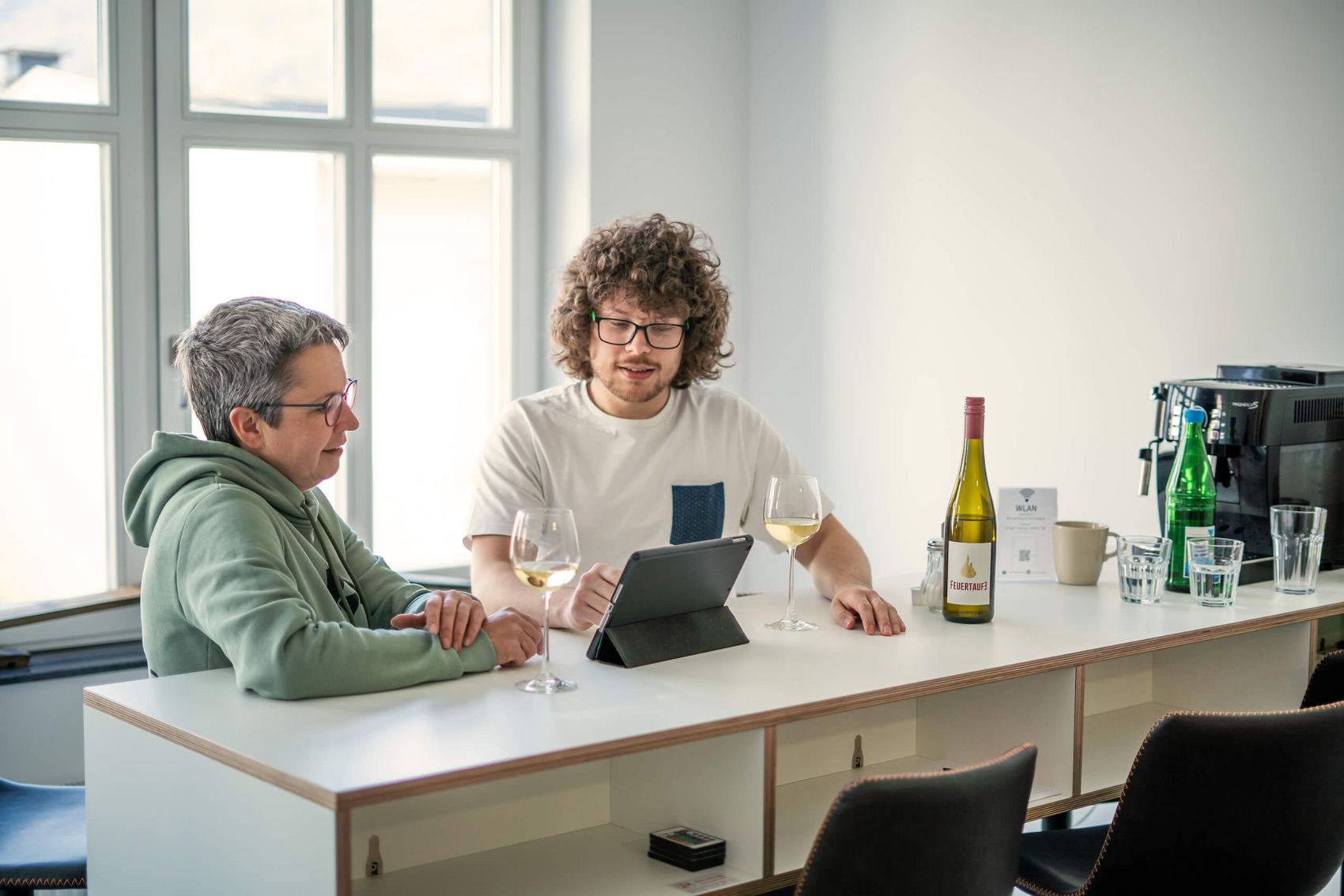Kein Afterwork ohne Riesling © Alexander Plattner, MoselWerk Coworking Lockeres Austauschgespräch zwischen zwei Kollegen mit Tablet und Wein