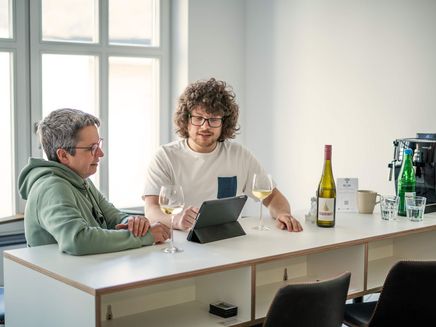 Kein Afterwork ohne Riesling © Alexander Plattner, MoselWerk Coworking Lockeres Austauschgespräch zwischen zwei Kollegen mit Tablet und Wein