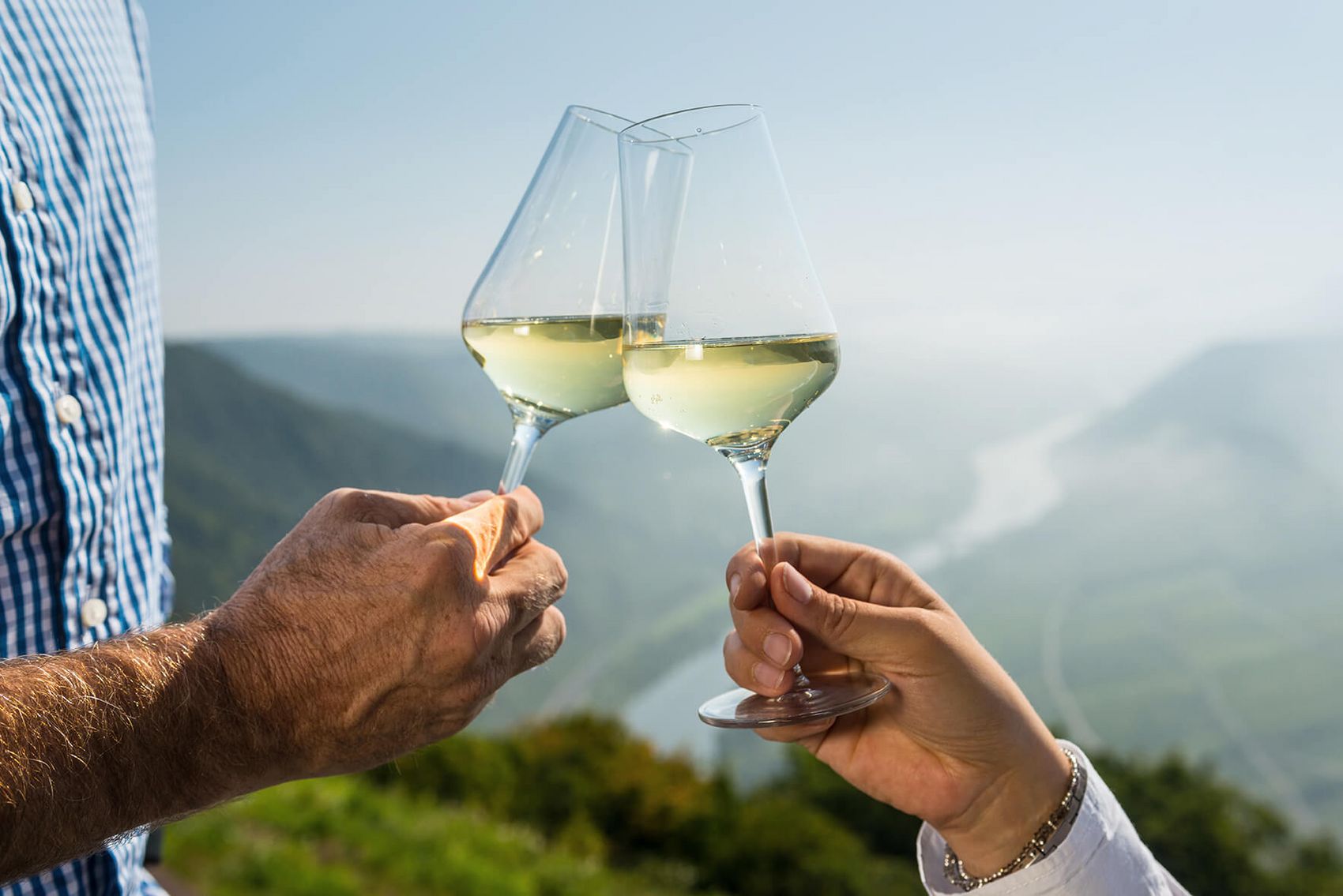 Bremm, Moselschleife © Rheinland-Pfalz Tourismus GmbH/Dominik Ketz Ansicht auf zwei Weingläser im Sonnenlicht und Blick auf die Moselschleife bei Bremm.