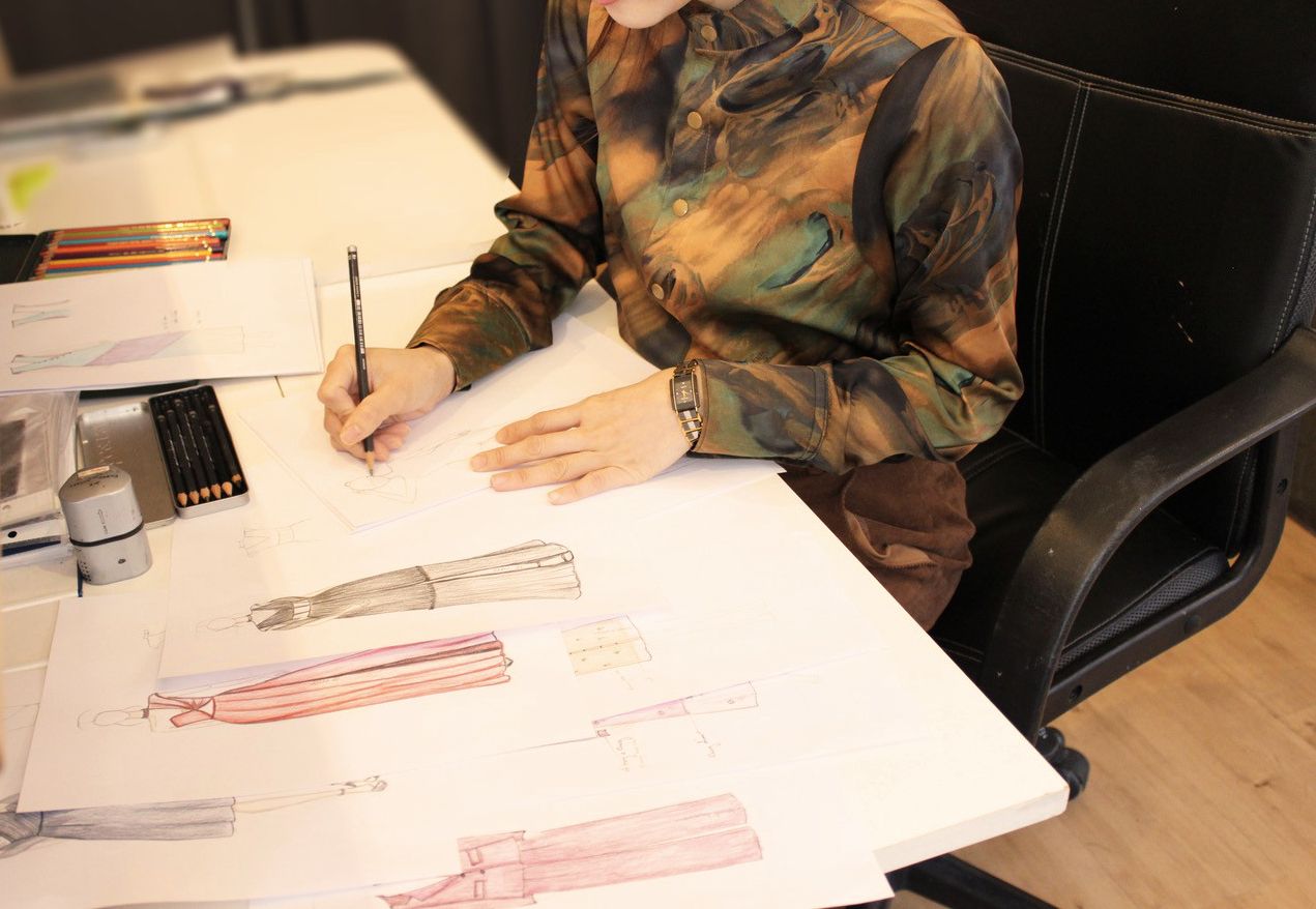 Trierer Designerin bei der Arbeit © Le Mode Person zeichnet Modedesigns am Schreibtisch