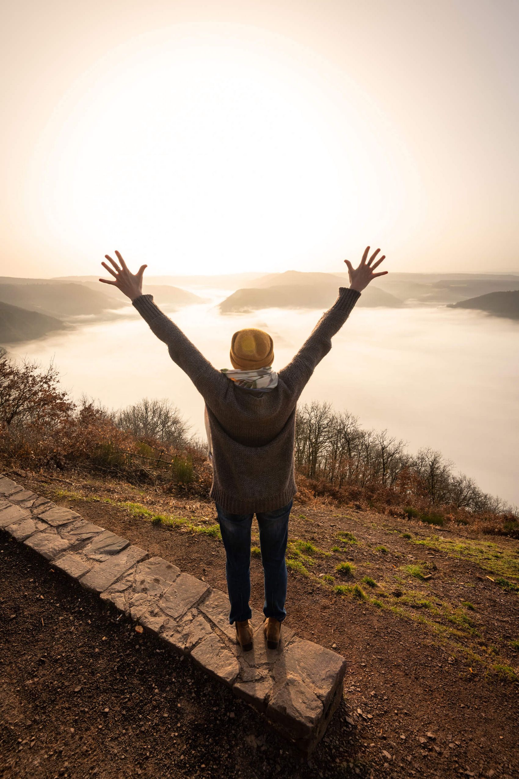 Bremm, Calmont, Blick ins neblige Moseltal © D. Ketz / MLT GmbH Frau mit ausgestreckten Armen bei Sonne auf dem Gipfel des Bremmer Calmonts mit Blick in ein nebliges Tal