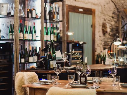 Traben-Trarbach, Gedeckter Tisch in der Vinothek Rustikal gedeckter Tisch in Vinothek mit Weinregal im Hintergrund