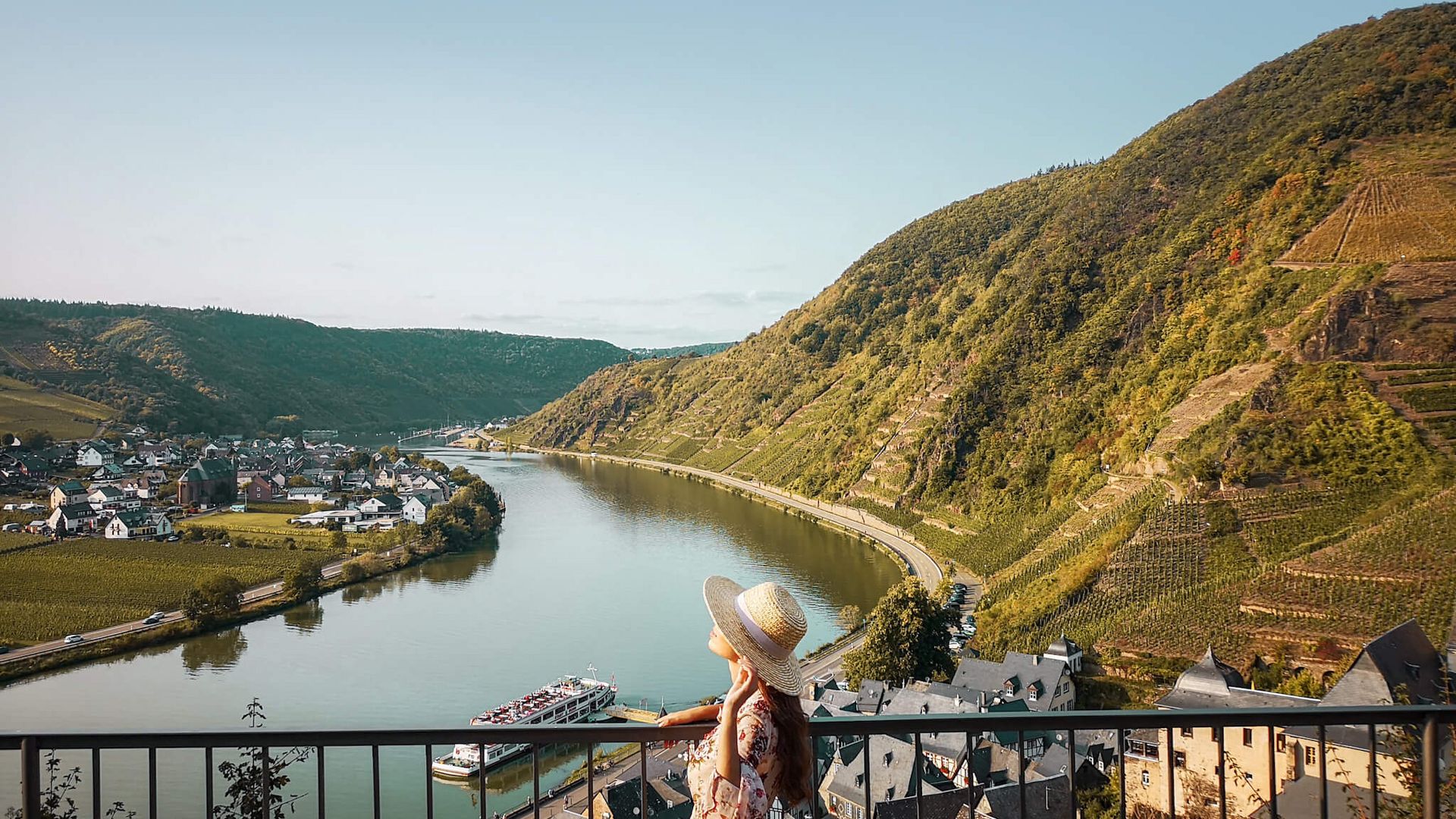 Ansicht auf eine Frau im Sommerkleid und Hut mit Ausblick auf die Moselschleife bei Beilstein.